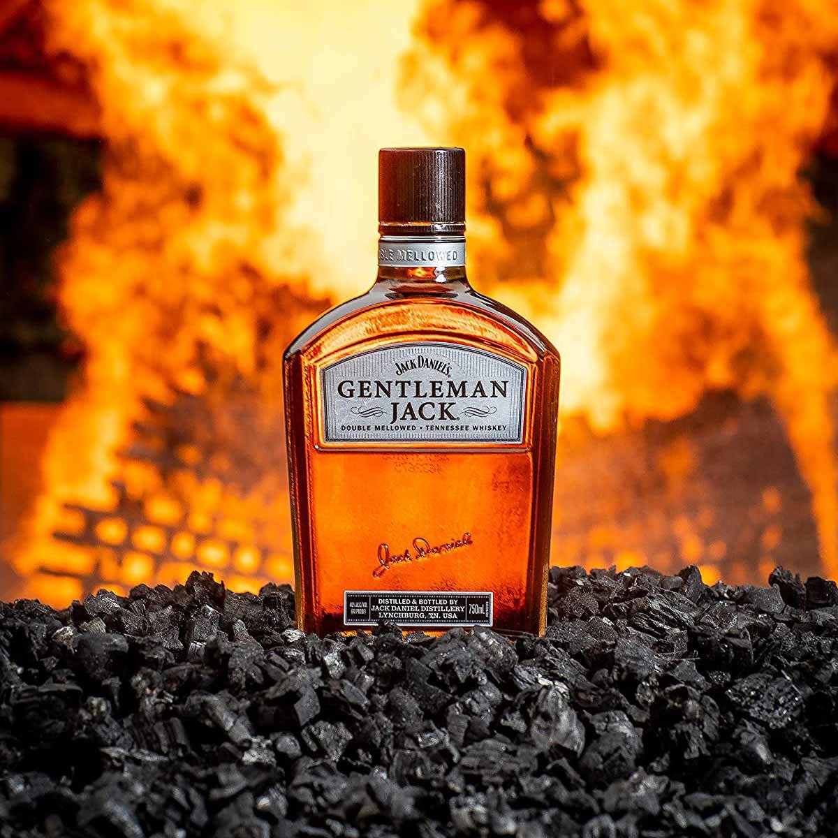 Lifestyle image of bottle resting on charcoal infront of flame
