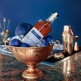 Lifestyle image of bottle resting in bowl of blue fruit